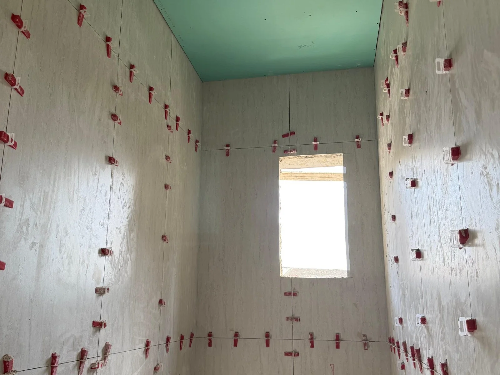 Large-format porcelain tiles being set on a wall